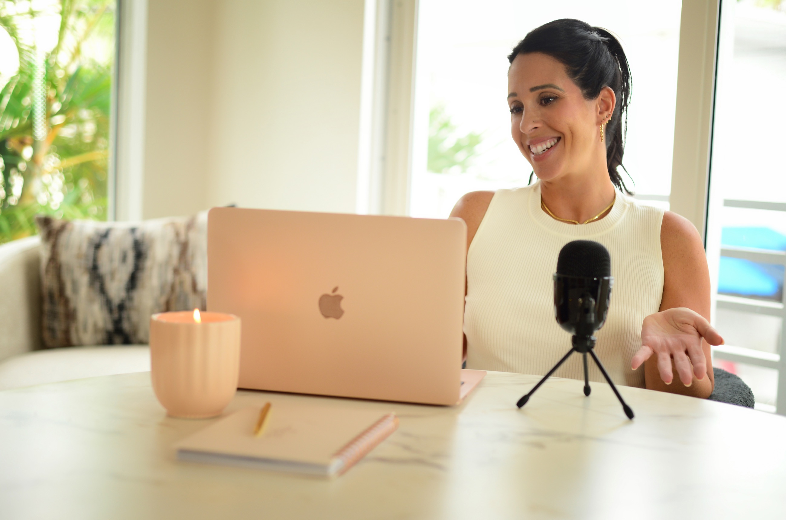 Jennifer Nicole recording at a marble table with a microphone and laptop