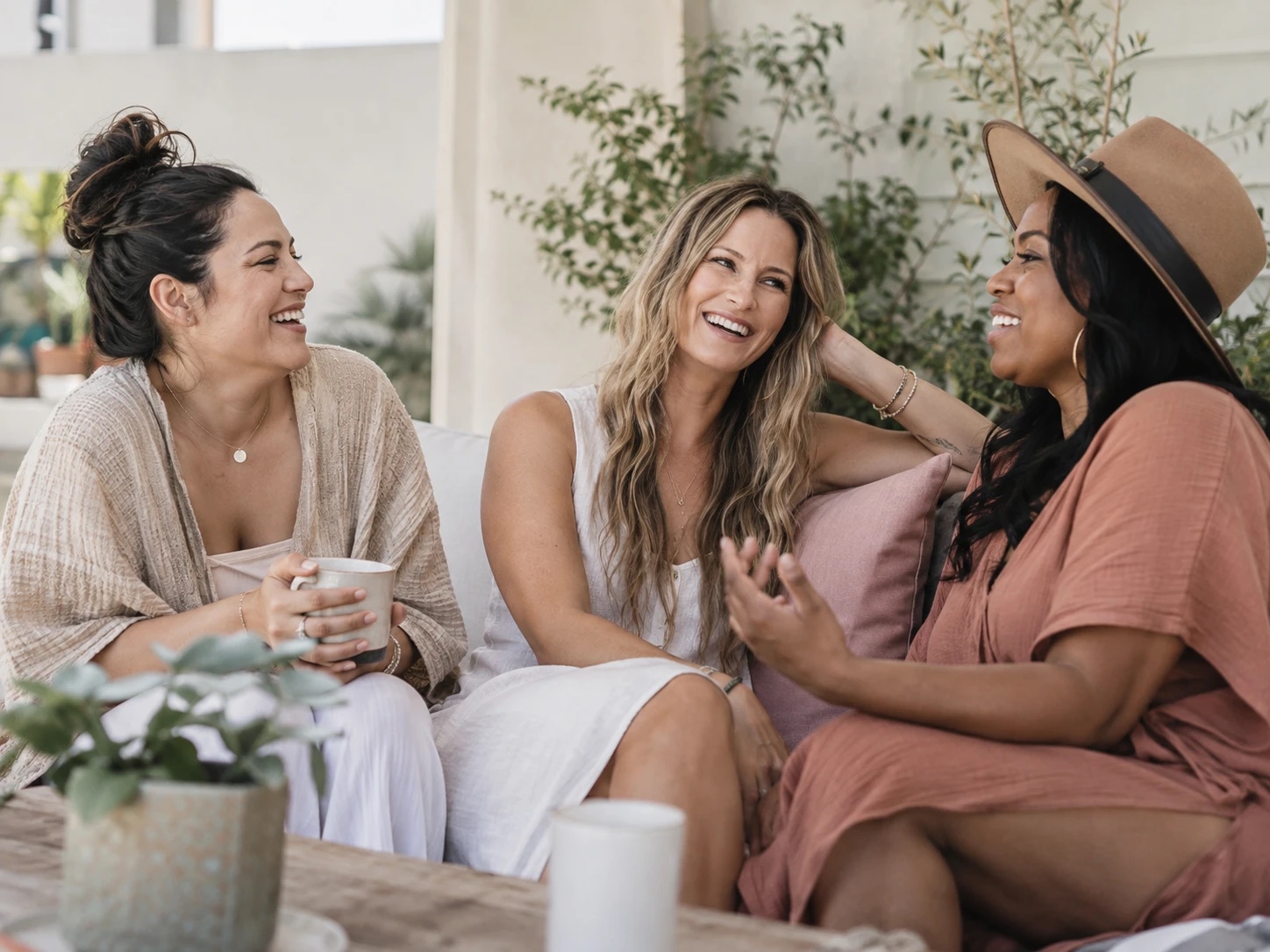 Three vibrant women in midlife laughing together over coffee